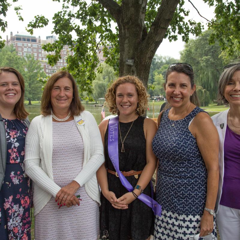 Five women stand outside smiling.