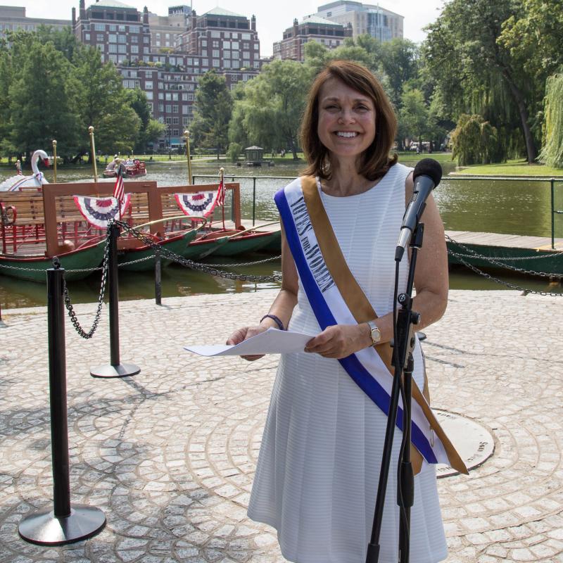 Woman wearing sash smiles.