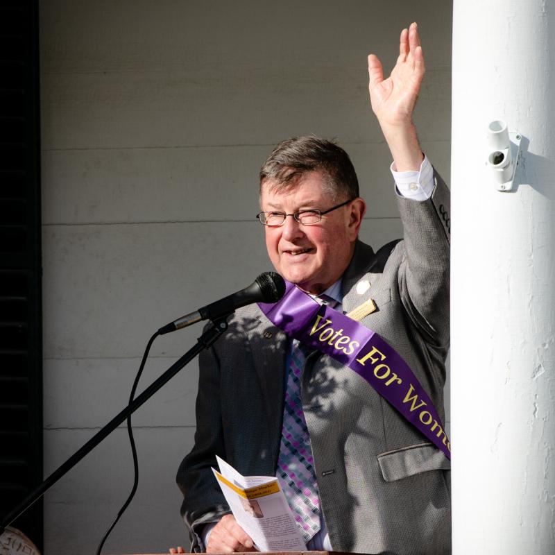 Man stands out podium outdoors speaking.