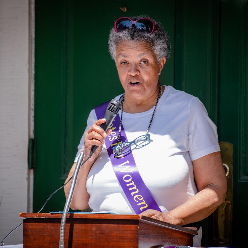 Woman stands at podium speaking.