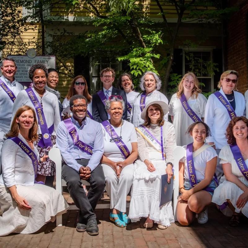 Large crowd in purple sashes outdoors.