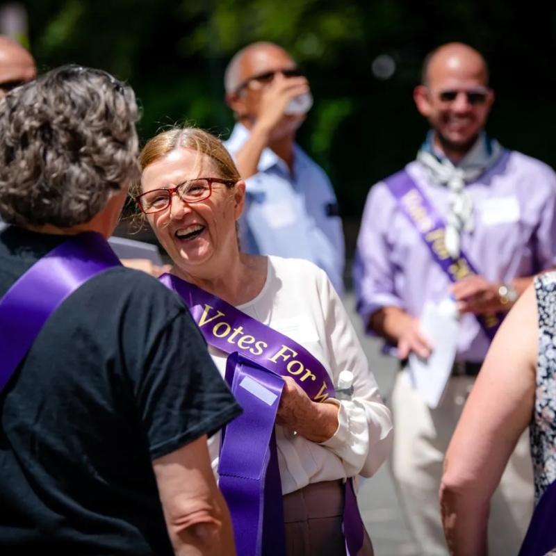 Woman outside wearing purple sash.