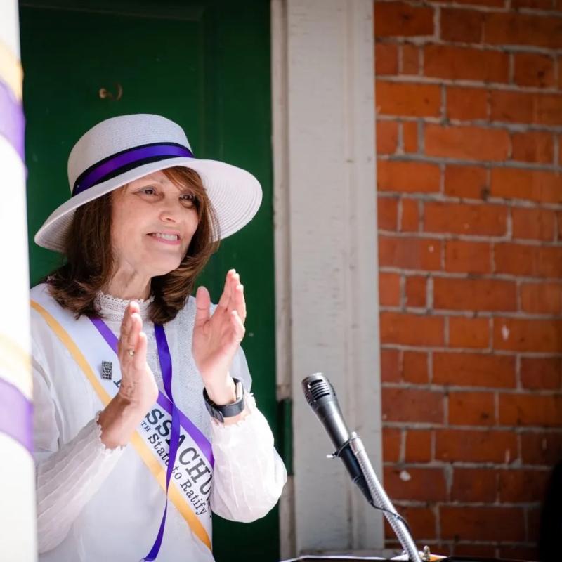 Woman stands at podium speaking.