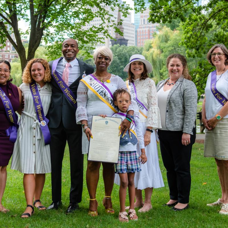 Eight people in purple sashes outdoors.