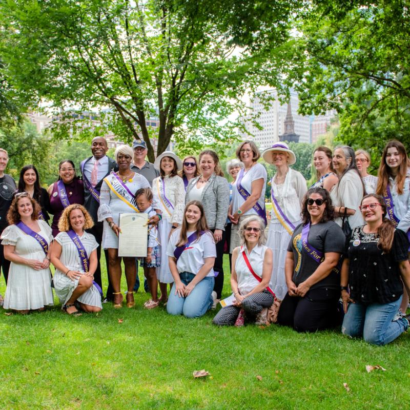 Large crowd in purple sashes outdoors.