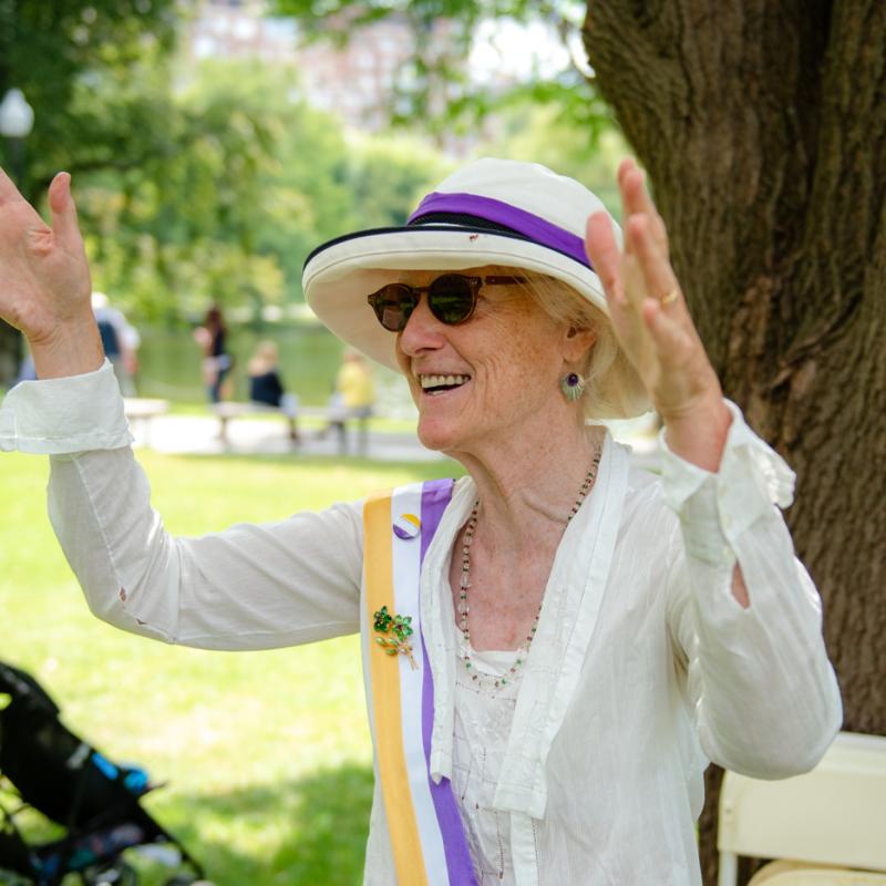 Woman in white stands outside smiling.