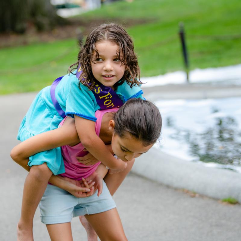 Two girls play piggyback.