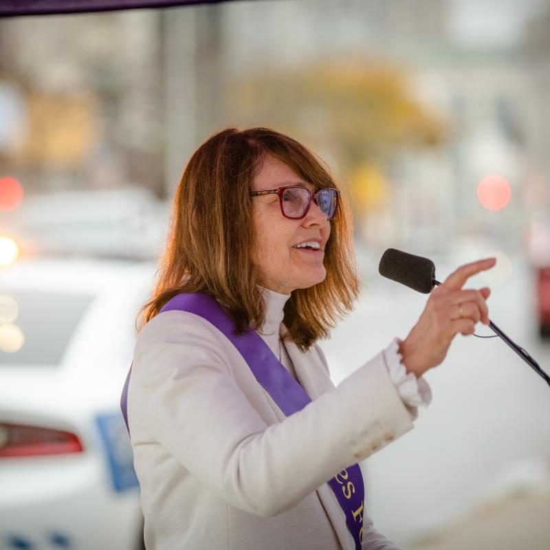 Woman stands at podium speaking.