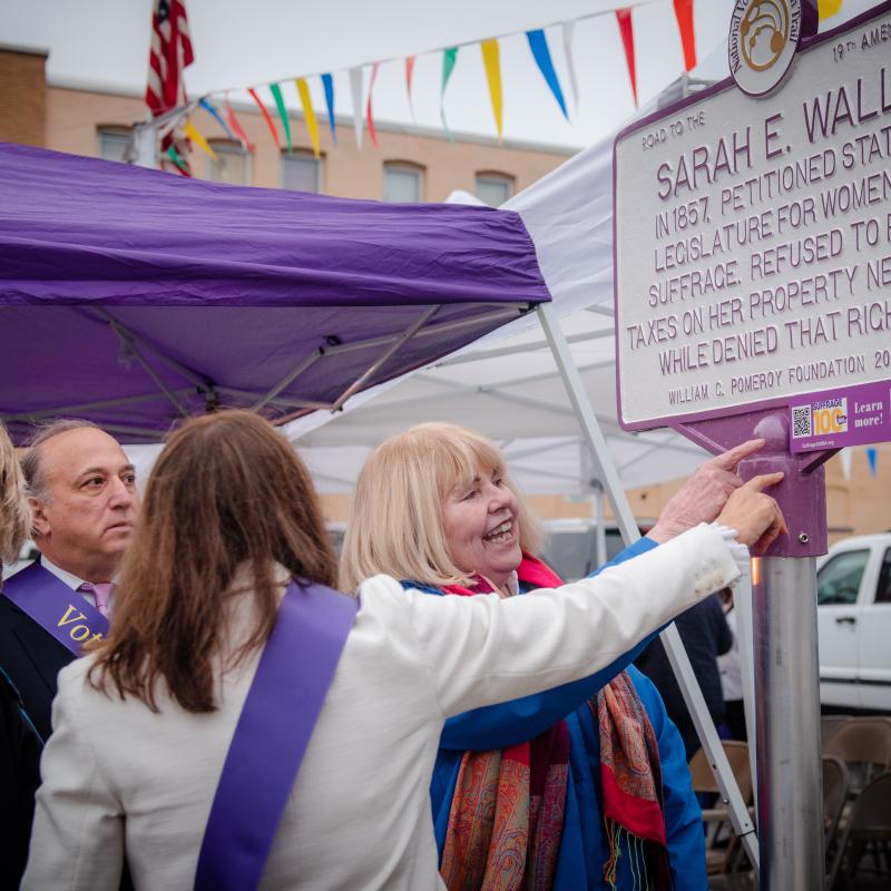 Woman looks at Sarah E. Wall suffrage marker.