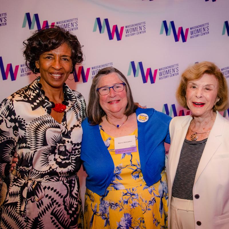 Three women stand in front of Massachusetts Women's History Center's step and repeat.