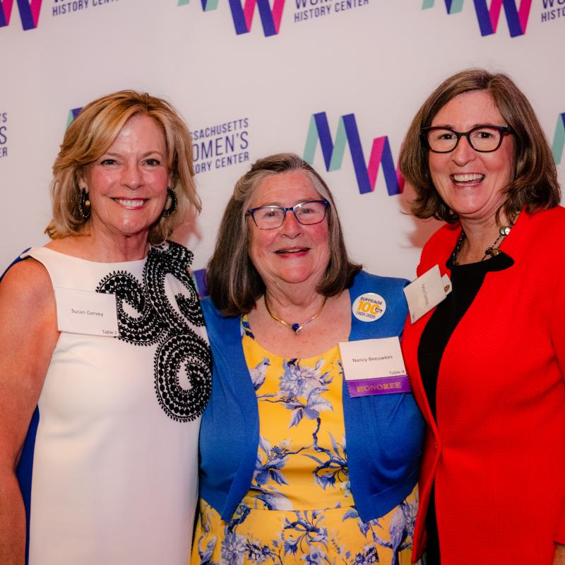 Three women stand in front of Massachusetts Women's History Center's step and repeat.