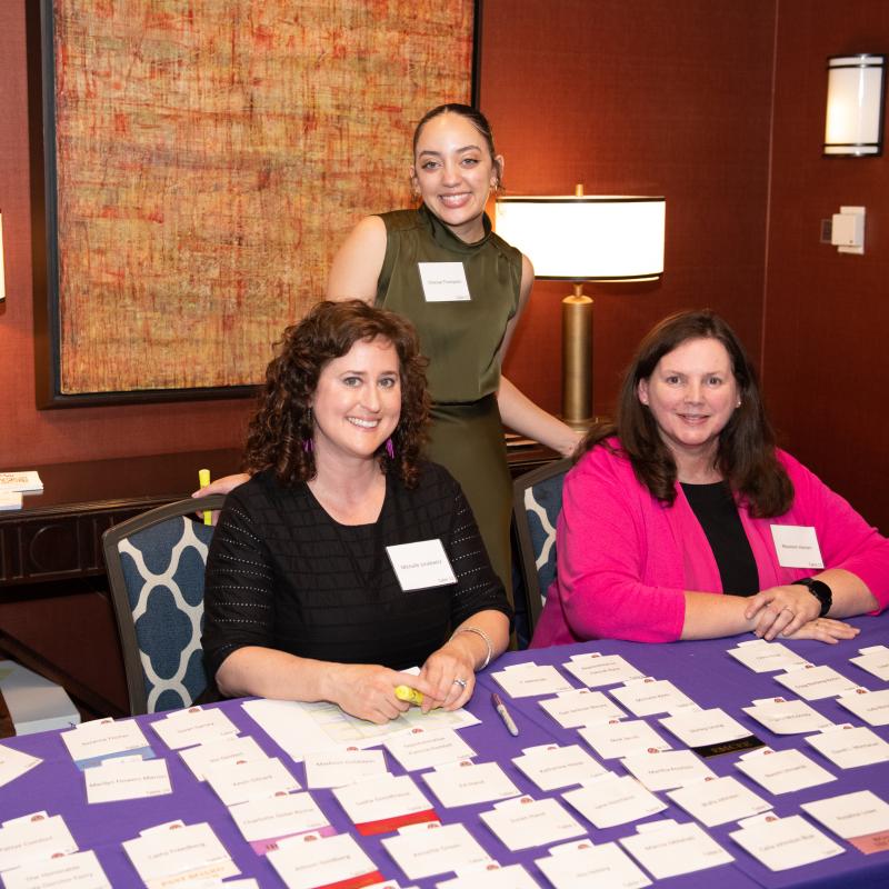 Three women sit at registration table.