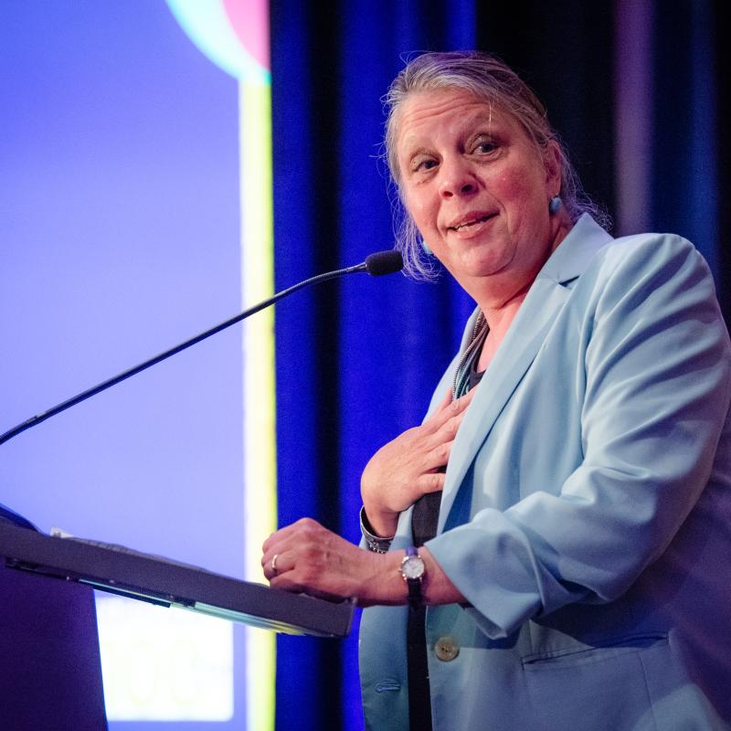 Woman stands at podium speaking.