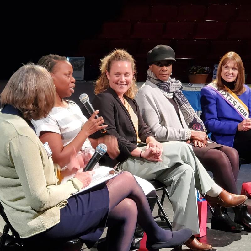 Group of people sit on stage speaking.