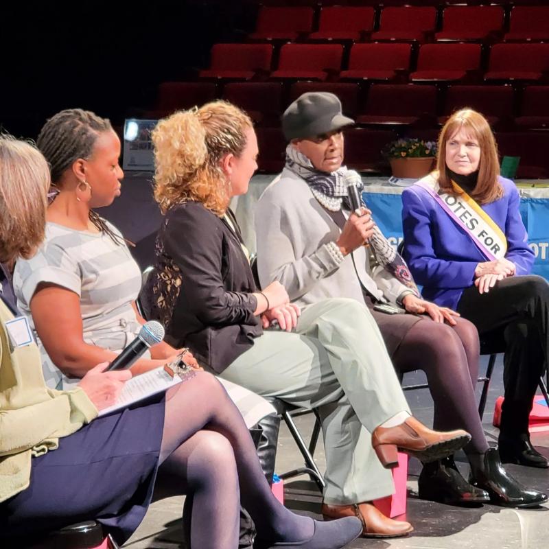 Group of people sit on stage speaking.