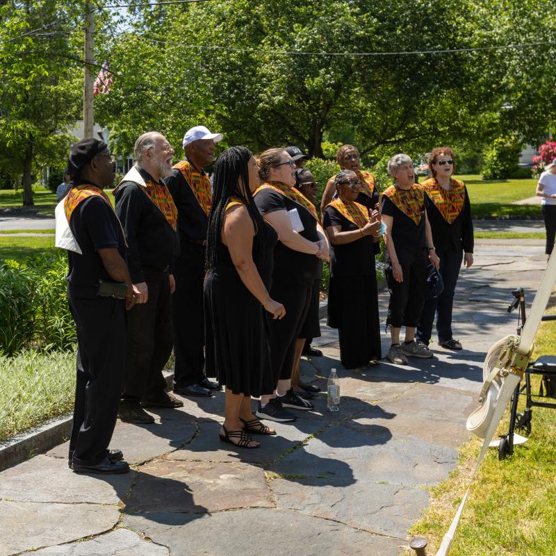 Group of adults stand outside singing.