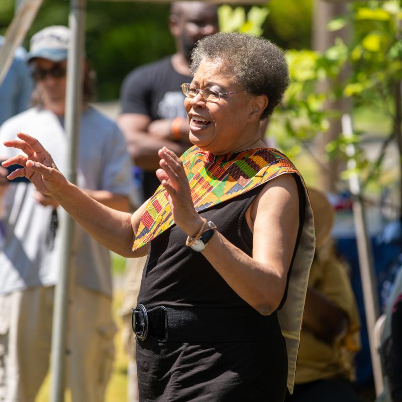 Woman stands outside conducting singers.