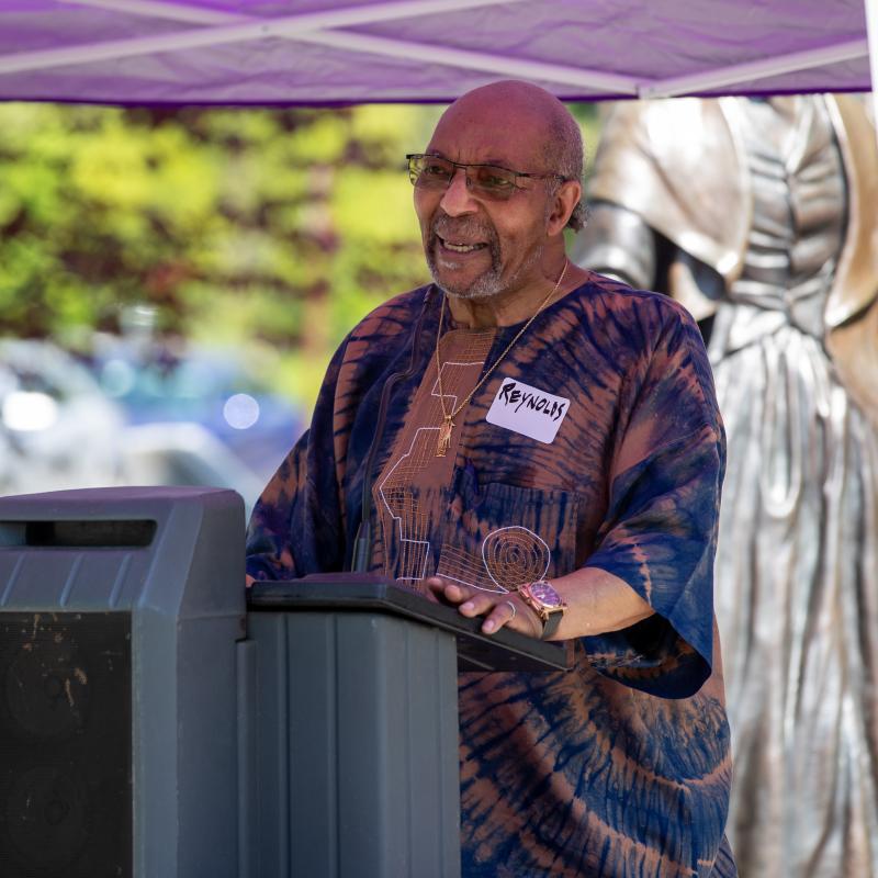 Man stands outside speaking at podium.