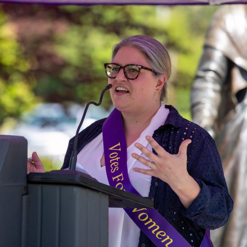 Woman stands at podium speaking.