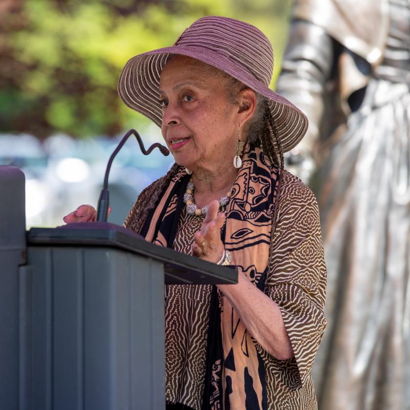 Woman stands at podium speaking.