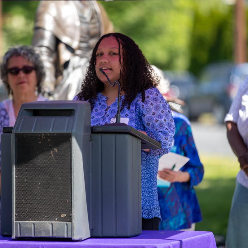 Woman stands at podium speaking.