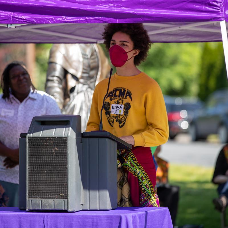 Man stands out podium outdoors speaking.