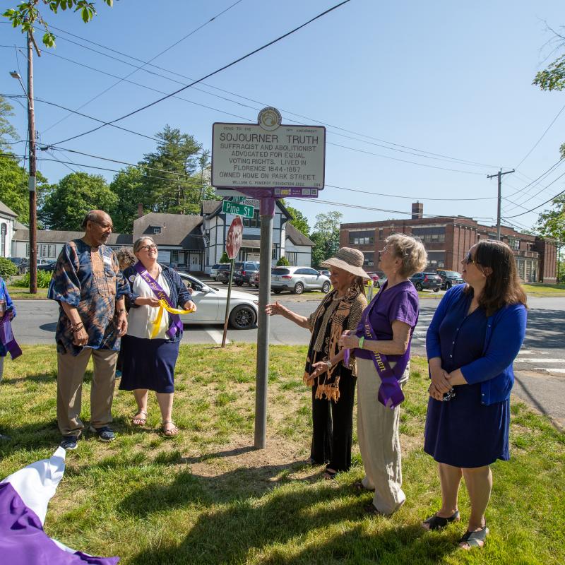 Group stands next to purple and white Sojourner Truth women's suffrage marker.