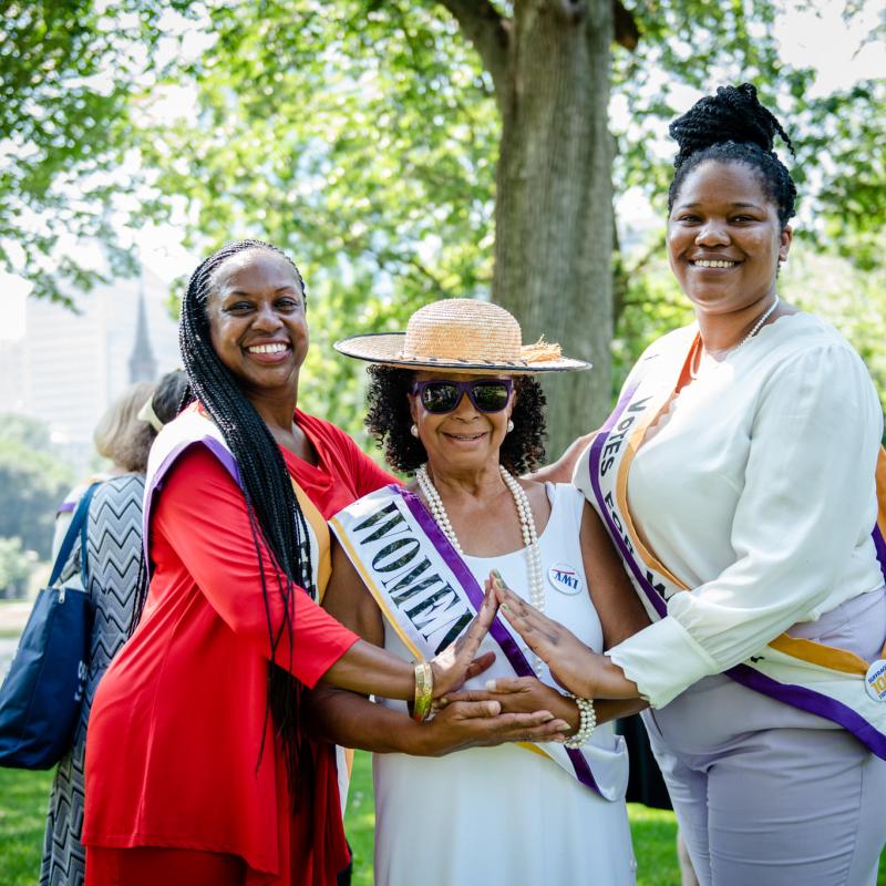 Three women stand outside smiling.