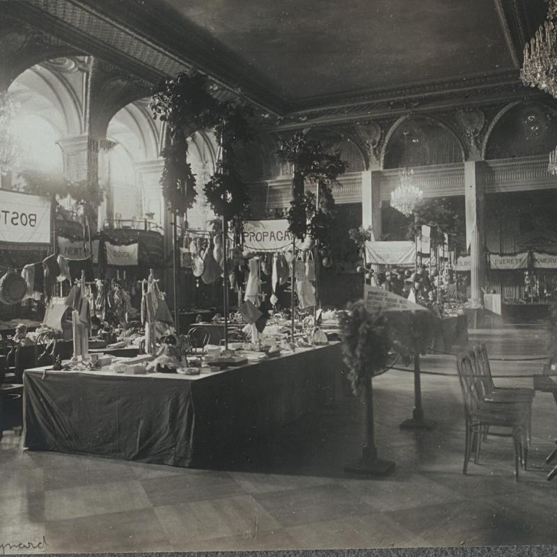 Black and white photograph of ornate room with multiple booths for suffrage bazaar