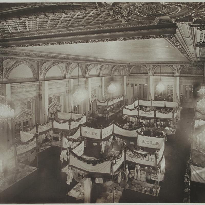 Black and white photograph of ornate room with multiple booths for suffrage bazaar