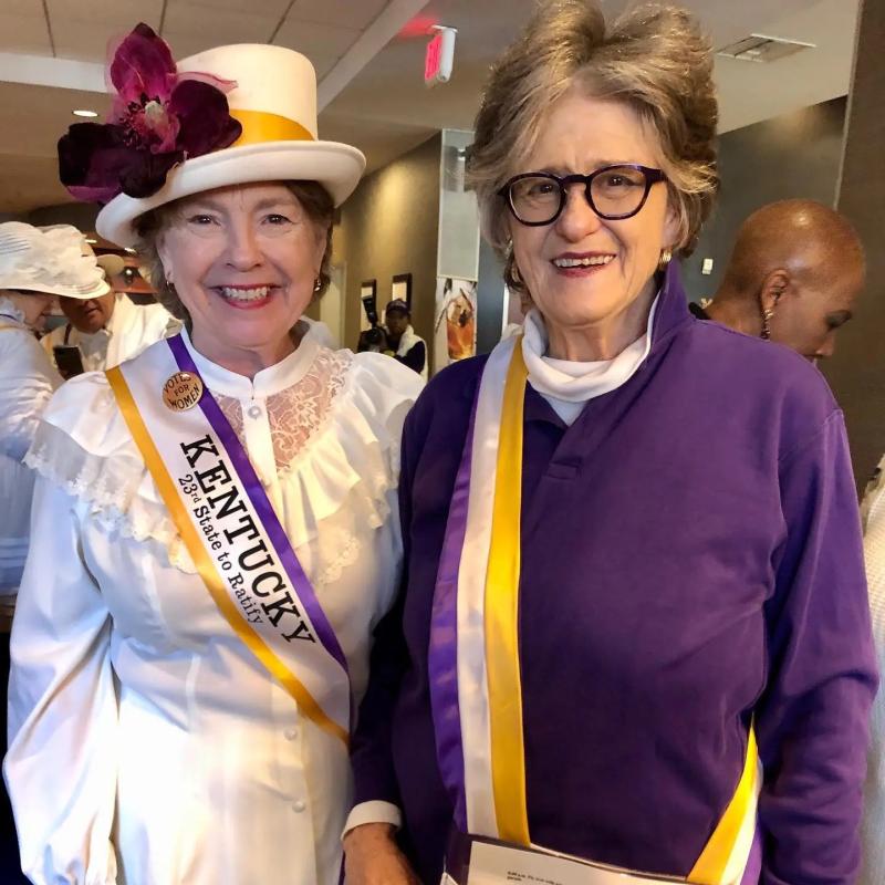 Two women wearing sashes.