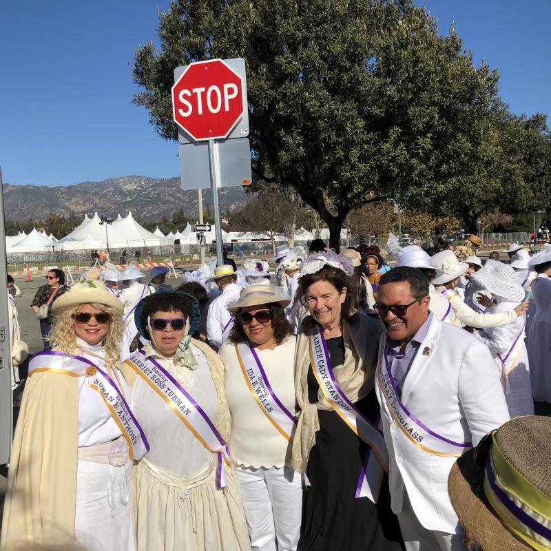 Five people wearing white and sashes.