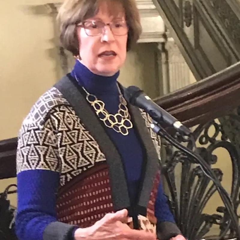 Woman stands at podium speaking.