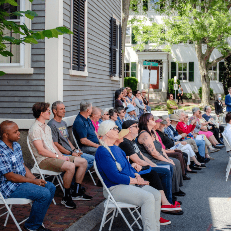 Audience sits outside.