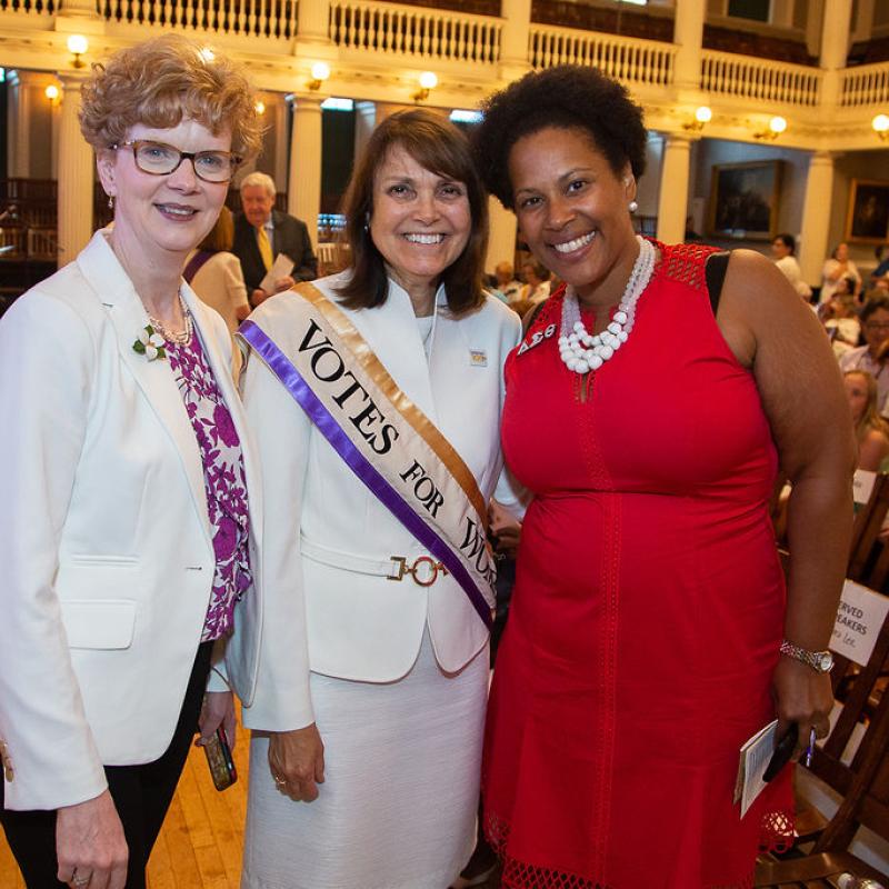 Three women smile at camera.