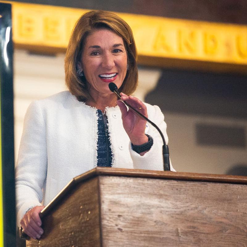 Woman stands at podium speaking.