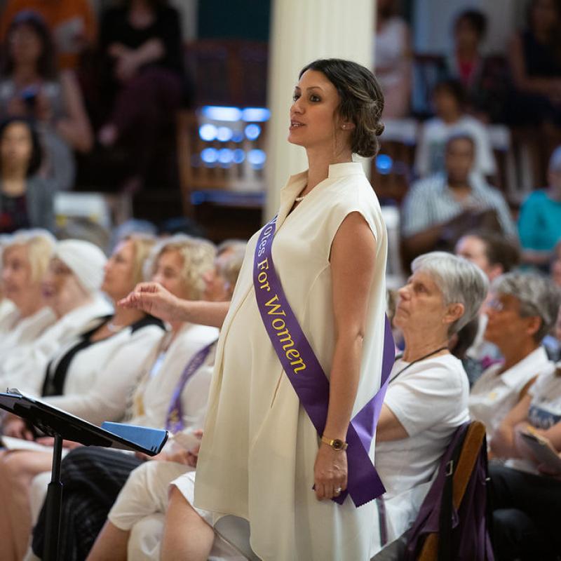 Woman in white stands in front of audience.