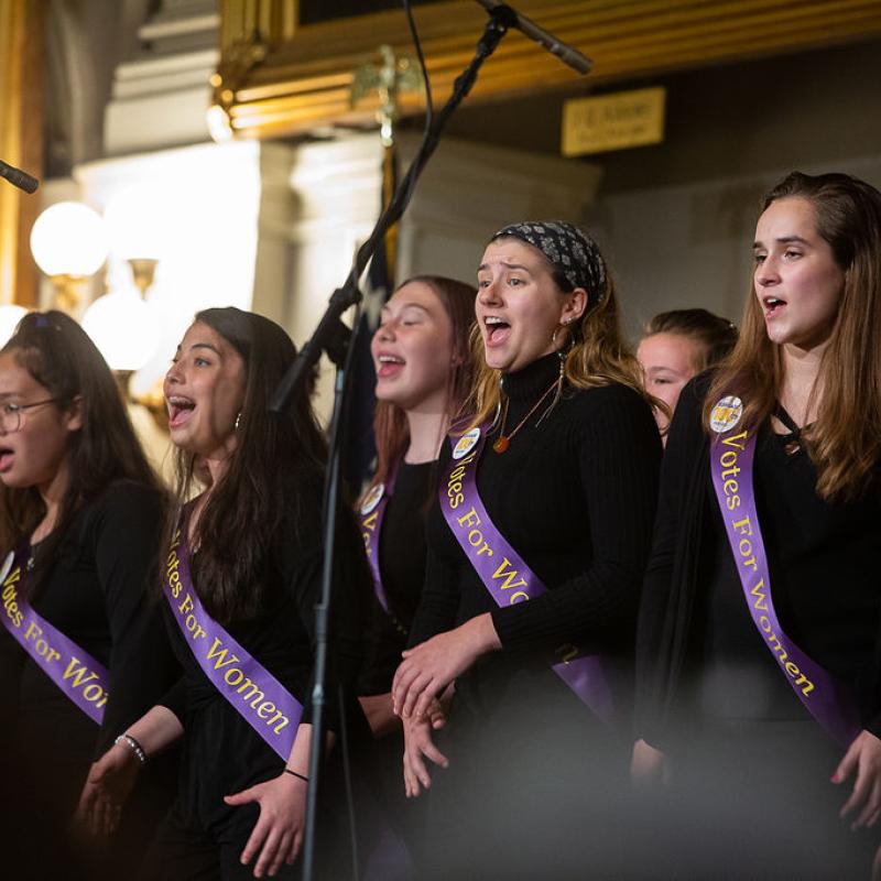 Group of teenagers sing on stage.