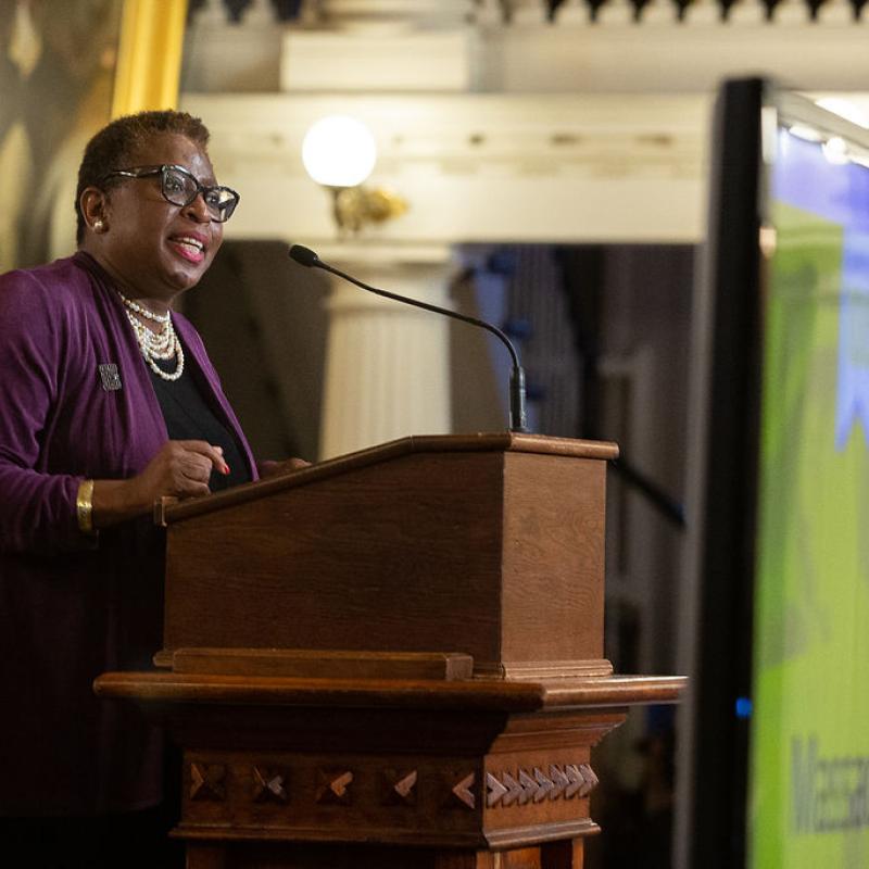 Woman stands at podium speaking.