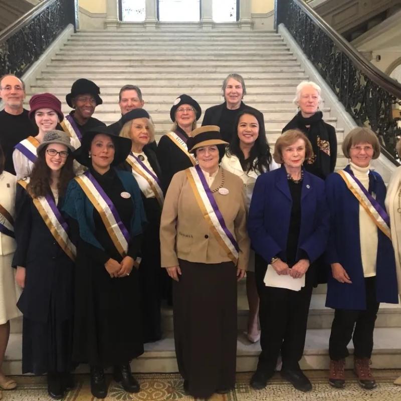 Group stands in front of stairs, smiling.