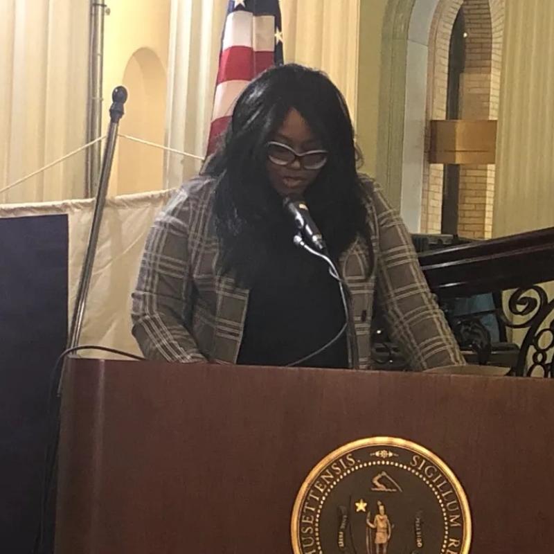 Woman stands at podium speaking.