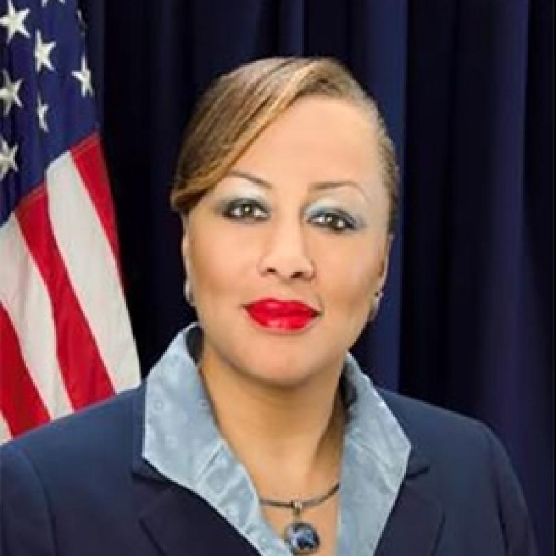 hadshot of Celia Blue smiling and sitting in front of an American flag