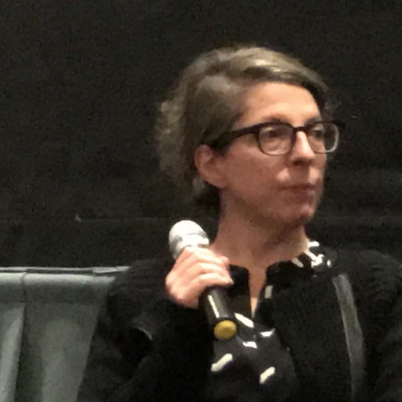 Woman stands in movie theater, speaking.