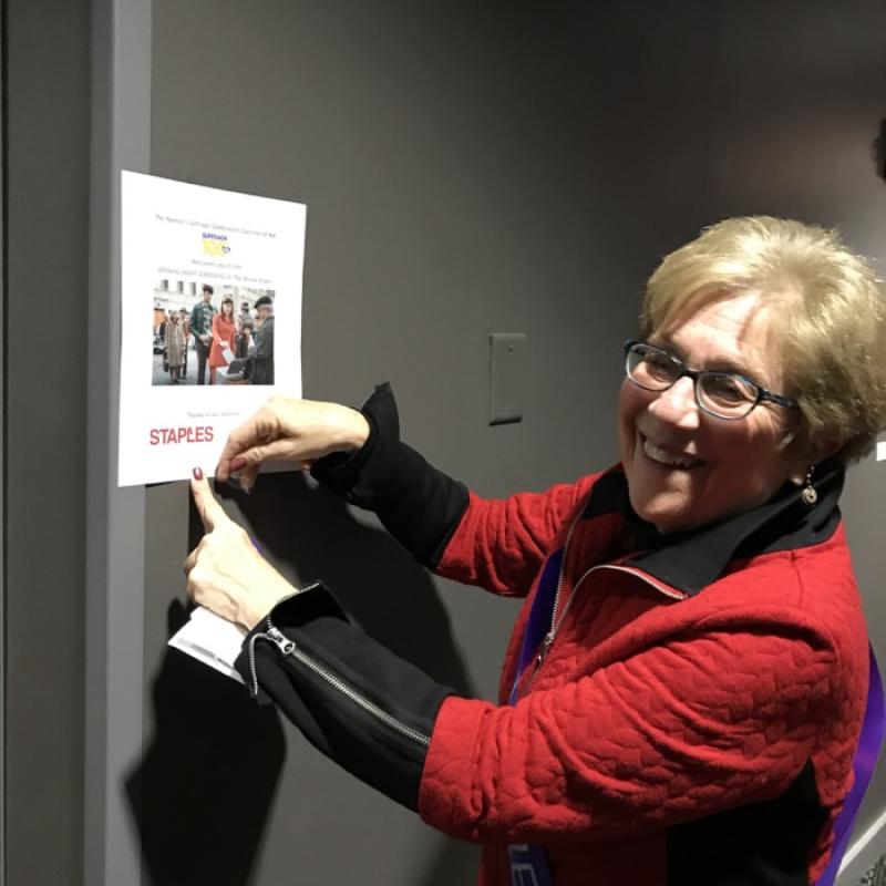 Woman points to sign for The Divine Order film screening.