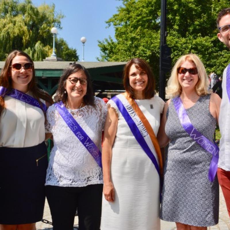 Six adults wearing sashes smiling.