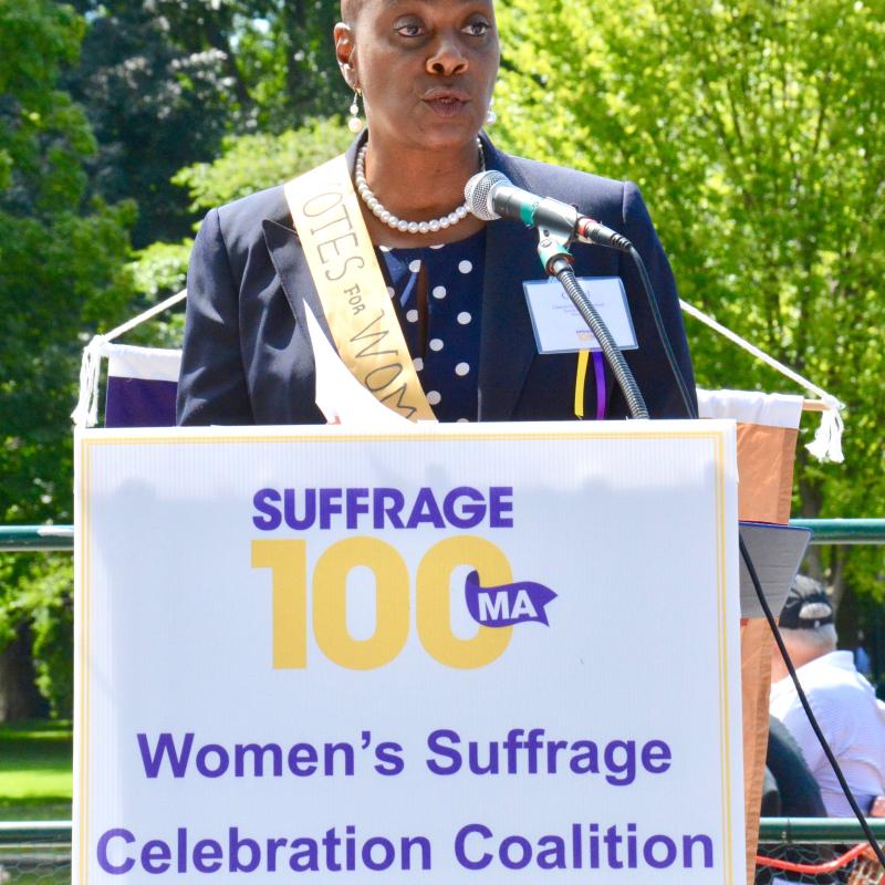 Woman stands at podium speaking.