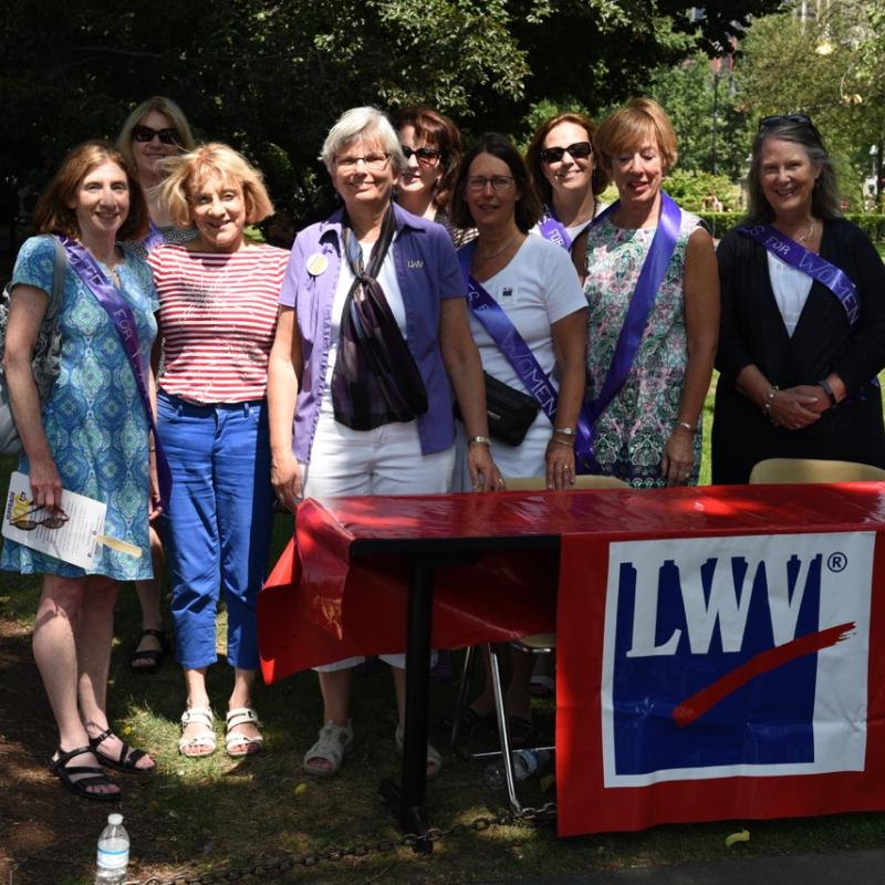 Eight women wearing purple sashes.