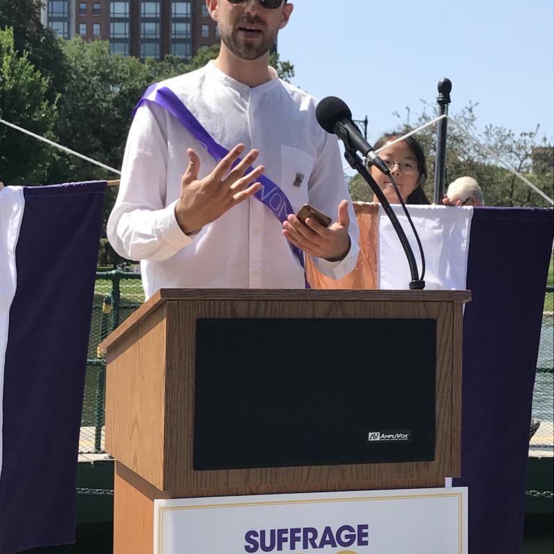 Man speaking at lectern outside.