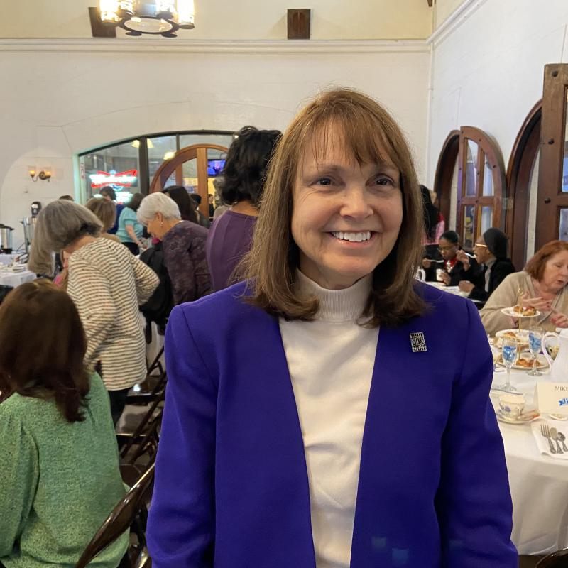 Woman stands indoors smiling.