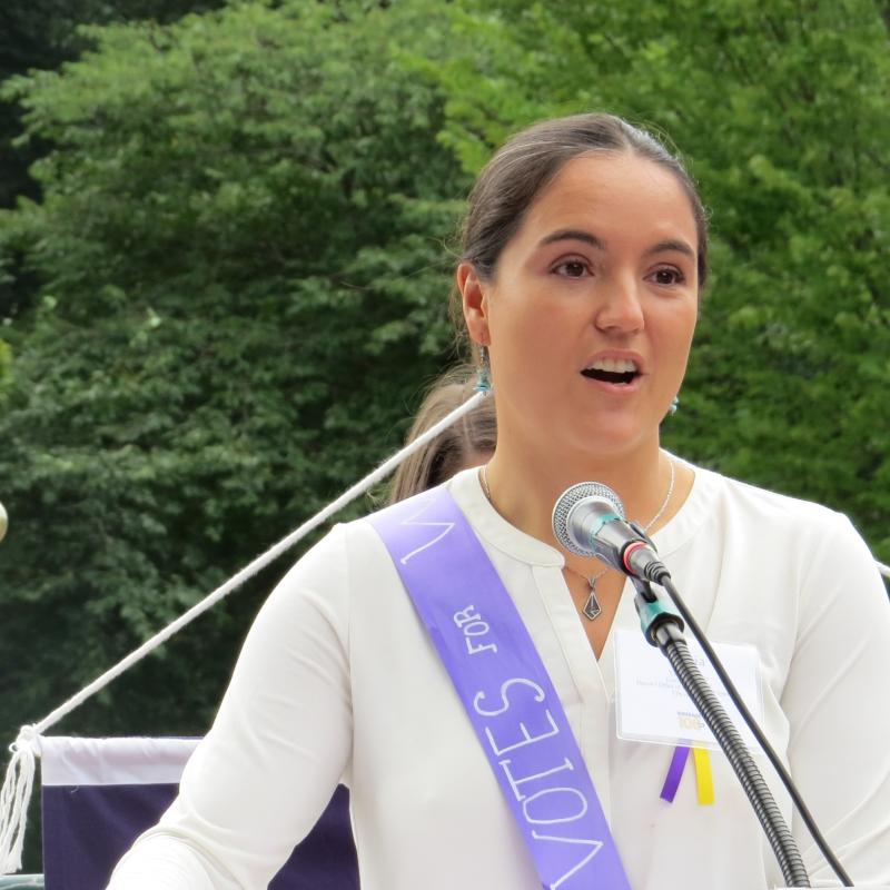 Woman stands at podium speaking.